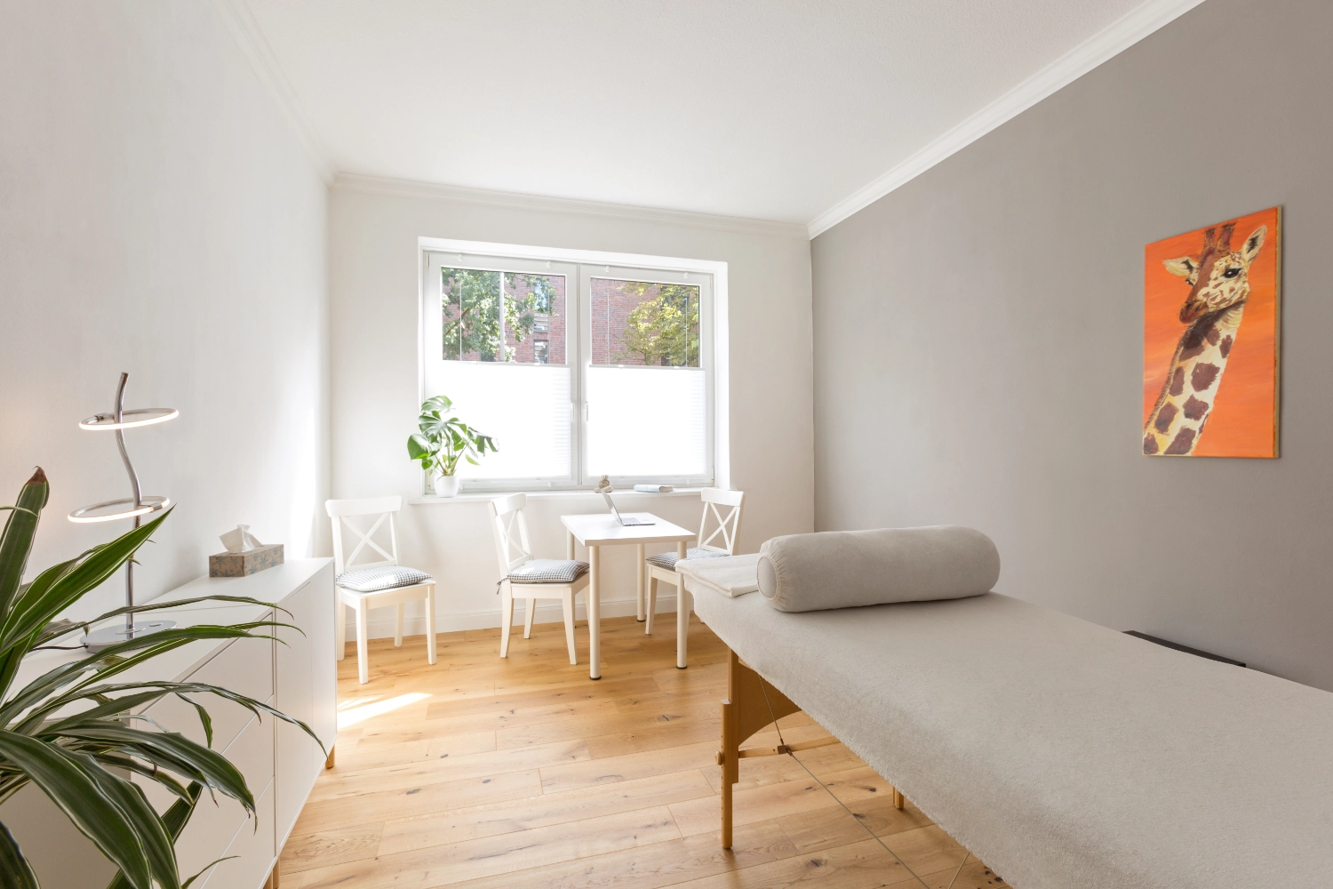 Heller und moderner Behandlungsraum mit Massageliege, Sitzgruppe, Holzfußboden und entspannender Atmosphäre – ideal für Osteopathie, Maren Brinkmann, Heilpraktikerin